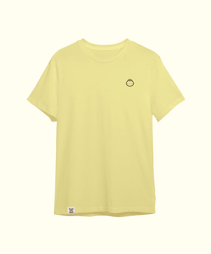Light yellow plain tee featuring a small, minimalistic mascot logo on the left chest, perfect for casual wear. Sun Bum.