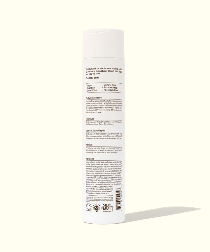 Back view of a white bottle of Curls Shampoo highlighting its ingredients and benefits for curly hair on a light background. The label features detailed product information. Sun Bum