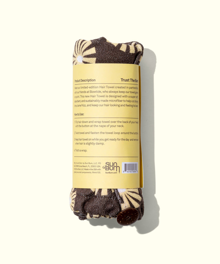 Limited edition SB x Slowtide hair towel rolled up with a beige and brown patterned design. Designed to dry hair faster and protect it against frizz, breakage, and dullness. Sun Bum