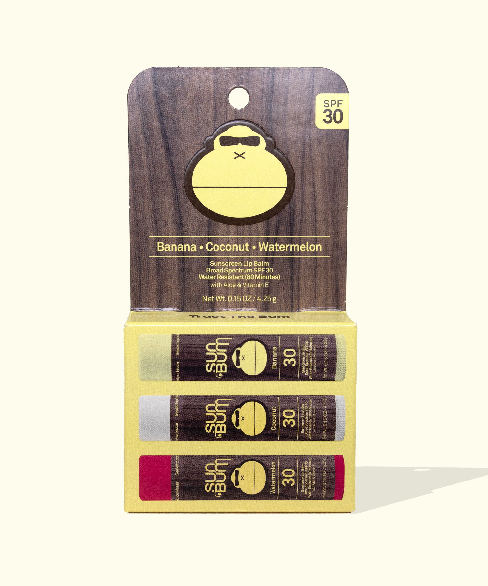 Original SPF 30 Sunscreen Lip Balm 3-Pack featuring banana, coconut, and watermelon flavors displayed in a wood-textured package with yellow monkey logo. Three lip balm tubes with SPF 30 protection in dark packaging with contrasting yellow details - by Sun Bum