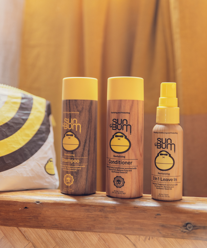 Sun Bum Hair Care Travel Essentials Kit featuring travel-sized shampoo, conditioner, and 3-in-1 leave-in spray, alongside a custom SPLASH-PROOF pouch by ALOHA Collection, perfect for travel, Sun Bum.